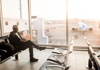 Airport Terminal: Businessman Uses Laptop Computer, Waiting for His Flight. Traveling Entrepreneur...