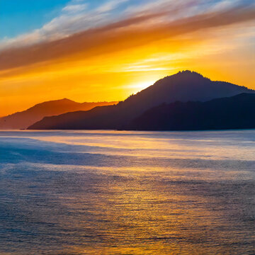 Panorama of a sunset over the ocean with mountains in silhouette image
