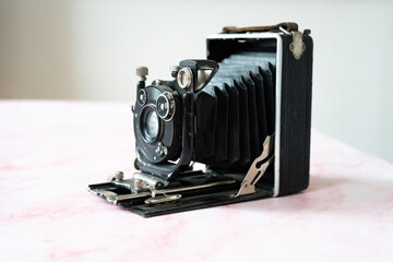 Appareil photo vintage à soufflet sur un fond en marbre rose - ancien appareil photo argentique - obrazy, fototapety, plakaty
