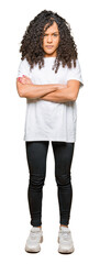 Obraz premium Young beautiful woman with curly hair wearing white t-shirt skeptic and nervous, disapproving expression on face with crossed arms. Negative person.