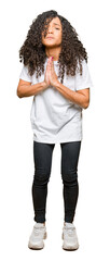 Fototapeta premium Young beautiful woman with curly hair wearing white t-shirt begging and praying with hands together with hope expression on face very emotional and worried. Asking for forgiveness. Religion concept.