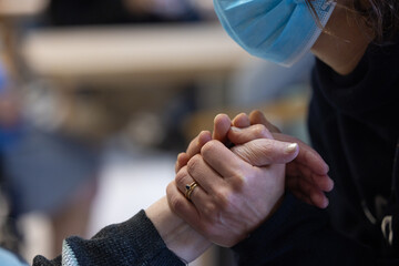 une personne avec un masque de protection tient les mains d'une personne âgée. Symbole de solidarité intergénérationnelle - obrazy, fototapety, plakaty