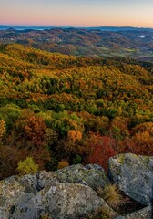 Scenic autumn morning sunrise on Sitno hill over Banska Stiavnica in Slovakia, colorful leaves of trees in forest on the mountains and beautiful light on sky.
