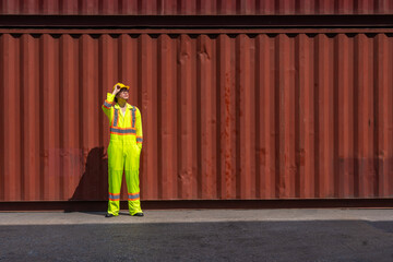 male engineer wearing a reflective colored uniform and helmet stands working in front of a...