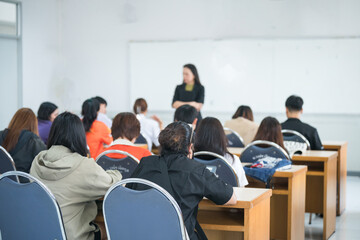 Rearview of college students listening to lecturer in the classroom