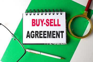 BUY-SELL AGREEMENT text on notebook on green paper