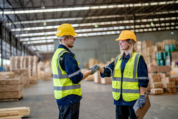 workers man and woman engineering walking and handshakeing with working suite dress at warehouse. Concept of smart industry worker operating. Wood factories produce wood palate