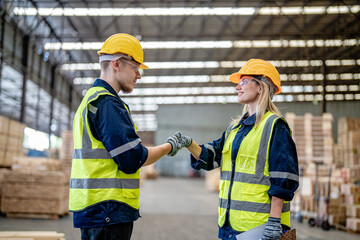 workers man and woman engineering walking and handshakeing with working suite dress at warehouse. Concept of smart industry worker operating. Wood factories produce wood palate