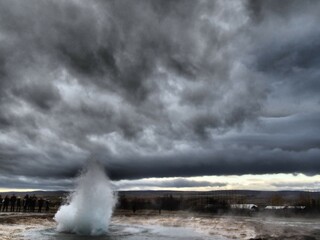 Haukadalur geothermal valley - geysir eruption with water and steam in the foreground, with...