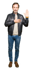 Middle age handsome man wearing black leather jacket Swearing with hand on chest and open palm,...