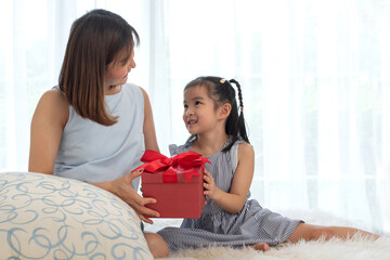 Little girl gives a gift to a baby inside the pregnant mother, family love and bonding