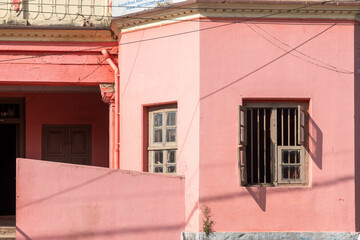 Pink walls of an old school with vintage square windows.