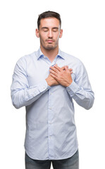 Handsome young businessman smiling with hands on chest with closed eyes and grateful gesture on face. Health concept.