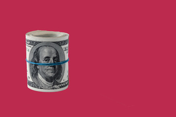 Roll of Paper money, background of one hundred dollar bills on a carmine red background. copy space.