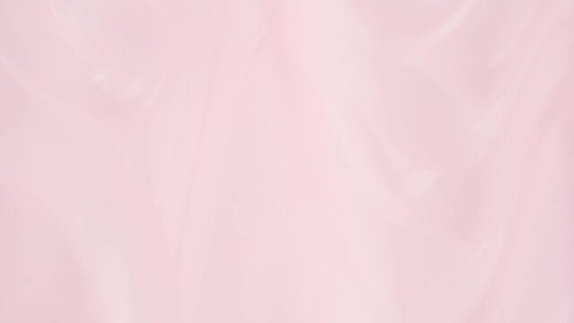 Liquid light pink cosmetics product, top view. Pink shower gel. Slow Motion. Shine glitter fluid pink metallic color paint.