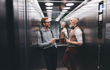 Confident colleagues discussing business strategy in modern elevator