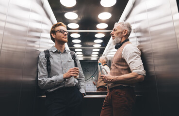 Confident businessmen standing in modern elevator and looking away © BullRun