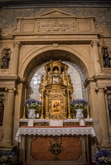 Detail of stonework altar with evangelist niches and arch with golden tabernacle in the center of tiles in low light, Dornes PORTUGAL