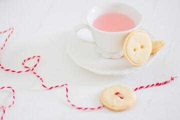 Button shaped handmade cookies and tea on white background. Flat lay, top view.
