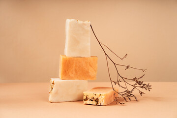 Patterns of natural handmade soap in different sizes and colors. Peach background natural materials, wood, dried flowers. Cosmetic pedestal for product promotion.