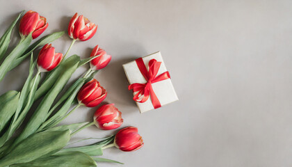 floral frame with red tulips and gift box, top view