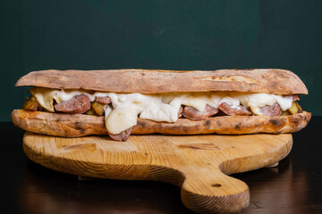 Panuozzo napoletano croccante con salsiccia, patate al forno e provola filante servito in un pub napoletano