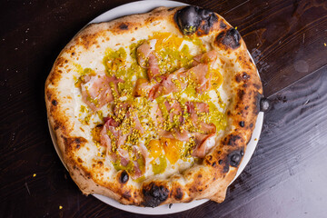 Pizza tradizionale napoletana con mortadella, pomodorino giallo, mozzarella e granella di pistacchio servita in una pizzeria