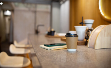Coffee cup with mobile placed on notebook on mable counter with coffee equipment for coffee drip on...