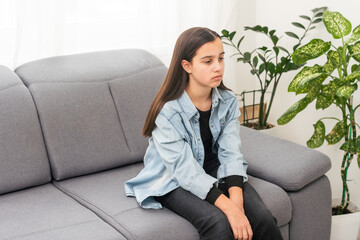 Beautiful young girl sitting on the sofa at home background. Copy space and mock up.