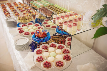Candy bar with different assortments of cakes. Delicious sweets on wedding candy buffet with desserts, cupcakes. 
