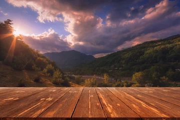 Fototapeten Summer beautiful background with sunset over mountains and empty wooden table in nature outdoor. Natural template landscape © soso