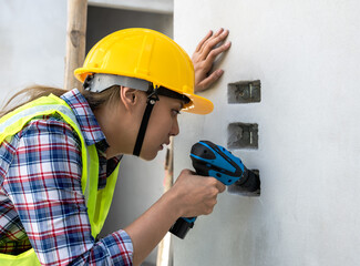Close up electrician woman working with drill in construction building site