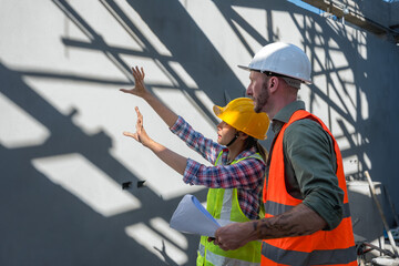 Male and female builders in safety vest and helmet working together in construction site