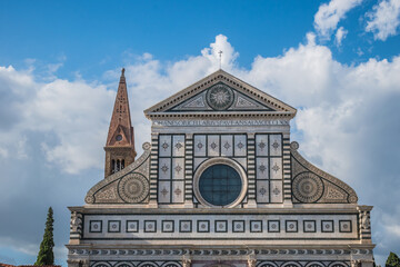 Detail of facade of Santa Maria Novella church with Latin inscription on the tympanum and Romanesque bell tower behind, Florence ITALY