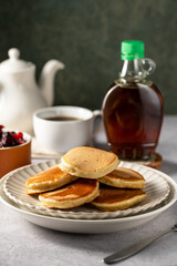 Stack of homemade american pancakes in a ceramic plate, served with syrup.