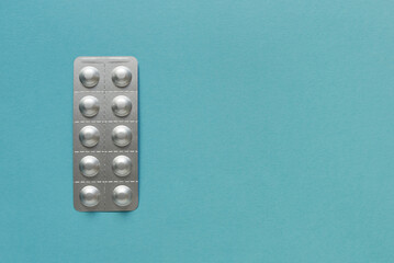 Medicine blister strip on a plain blue background. Pharmacy products. Medicine pills.	