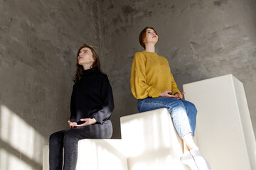 art photo of two young women looking up in casual clothes sitting on different levels of steps