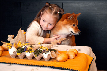 Cute and funny puppy and kid friends hugging. Girl sitting at kitchen table, coffee table. Red dog...