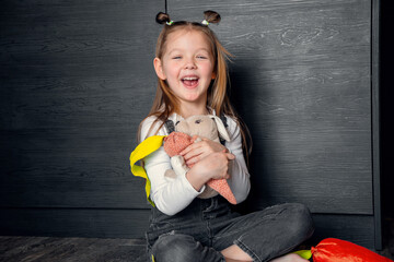 A girl with toys sitting on the floor and laughing. Different emotions, positive emotions, joy, happiness, smile, child, daughter