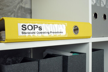 SOP Standard operating procedure concept. A yellow folder lies on an office shelf.