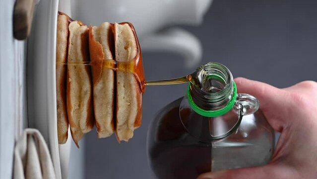 Pouring syrup over stack of pancakes. Homemade breakfast, vertical video