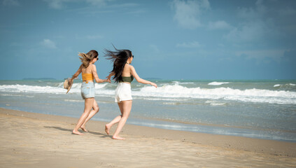 Fototapeta premium Portrait of two Happy traveller woman wearing straw enjoys her during summer tropical beach vacation