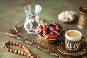 Cup of coffee and glass of water and dry dates on saucer ready to eat for iftar time. Islamic religion and ramadan concept.