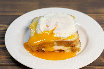 Croque madame, grilled sandwiches with sliced ham, melted cheese, dijon mustard and poached egg on  bechamel sauce.