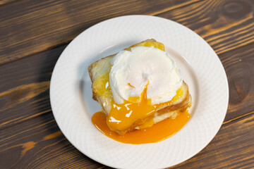 Croque madame, grilled sandwiches with sliced ham, melted cheese, dijon mustard and poached egg on  bechamel sauce.