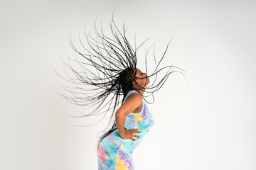 Plus size female model posing in colorful dress on white background, young African woman with curvy figure and pigtailed hairstyle, afro braids - obrazy, fototapety, plakaty