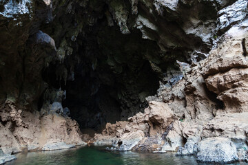 Dark cave in a rocky hill and blue water inside the cave. Thakhek, Laos