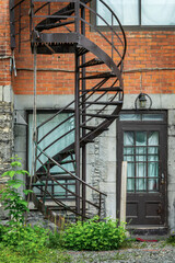 Fototapeta premium Rusty metallic outside spiral stairs on a brick building in Montreal, Canada
