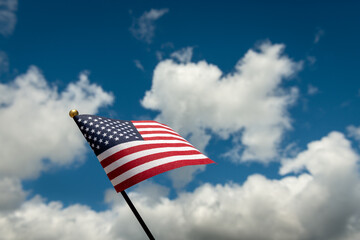 American flag waiving against blue sky and white clouds with copy space