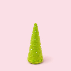 Pink background with handmade green yarn cone christmas trees. Organic decoration.
